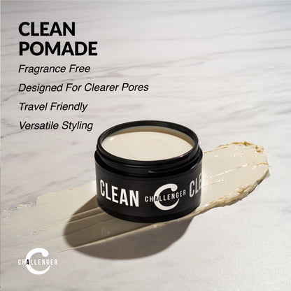 Open jar of Challenger Clean Pomade resting on a cream smear alongside product features on a white marble surface.